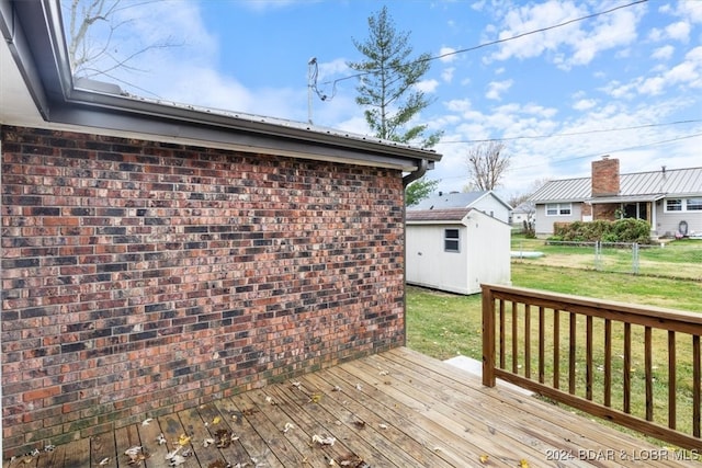 deck featuring an outbuilding, a yard, a storage unit, and fence