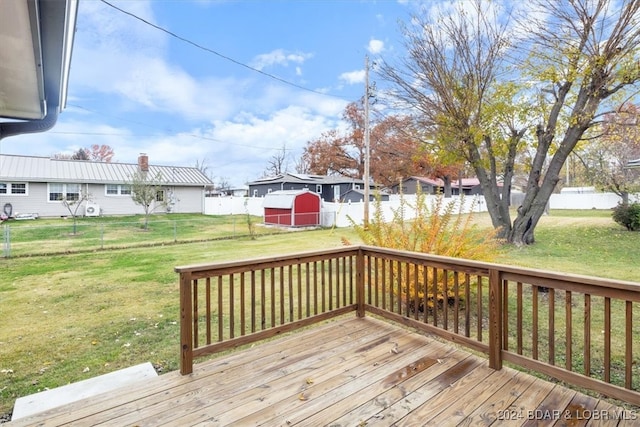 wooden terrace with a lawn, an outdoor structure, fence, and a residential view