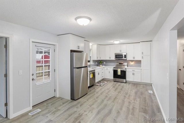 kitchen featuring a sink, visible vents, white cabinetry, light countertops, and appliances with stainless steel finishes