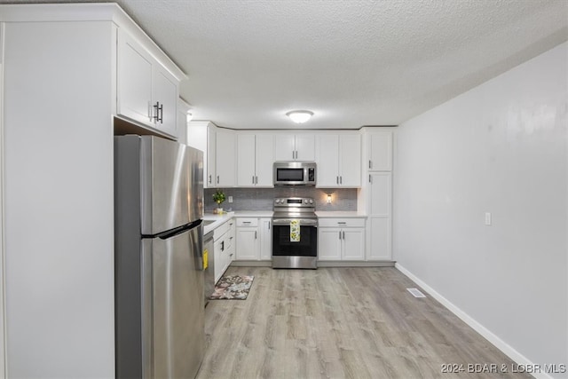 kitchen featuring decorative backsplash, appliances with stainless steel finishes, light wood-type flooring, a textured ceiling, and white cabinetry