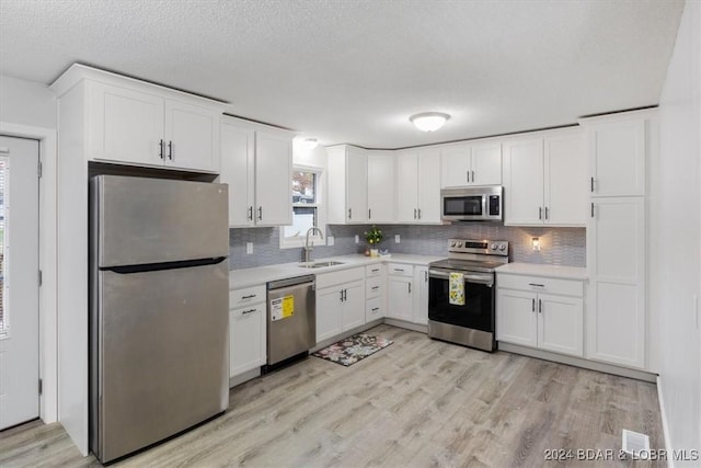 kitchen featuring stainless steel appliances, a sink, light countertops, and white cabinets