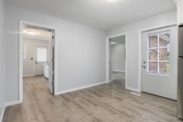 unfurnished room with light wood-type flooring, a healthy amount of sunlight, and baseboards