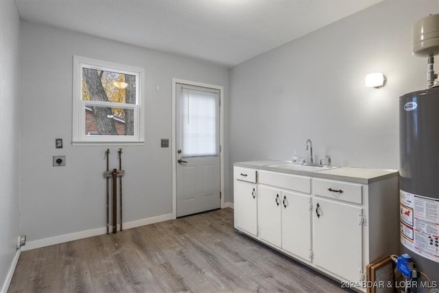 laundry room featuring cabinet space, water heater, light wood-style floors, a sink, and electric dryer hookup