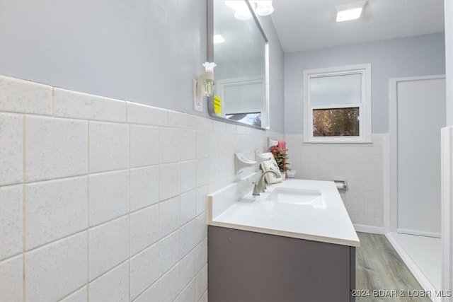 bathroom with tile walls, wainscoting, vanity, and wood finished floors