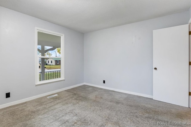 carpeted spare room with visible vents, a textured ceiling, and baseboards