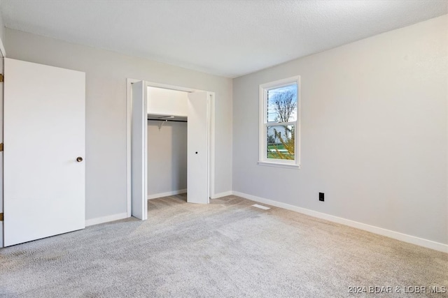 unfurnished bedroom with carpet, a closet, and baseboards