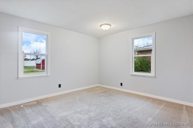 empty room with carpet, visible vents, and baseboards