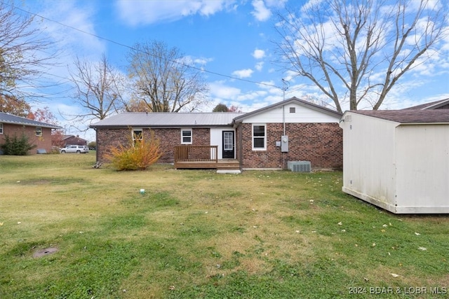 back of property with an outbuilding, a storage shed, brick siding, a yard, and a wooden deck