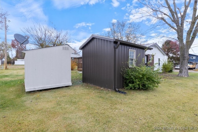 view of side of property featuring a storage shed, a yard, board and batten siding, and an outdoor structure