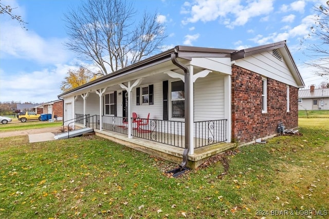 view of front facade featuring covered porch, a front lawn, and brick siding