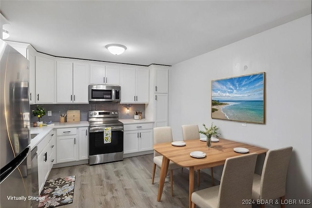 kitchen with white cabinets, decorative backsplash, light wood-style flooring, stainless steel appliances, and light countertops