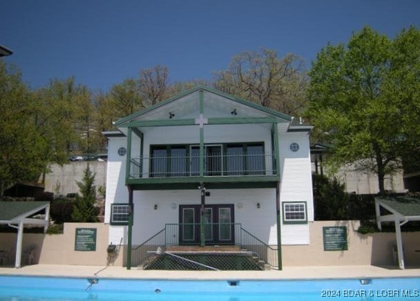 rear view of property featuring a balcony and a community pool