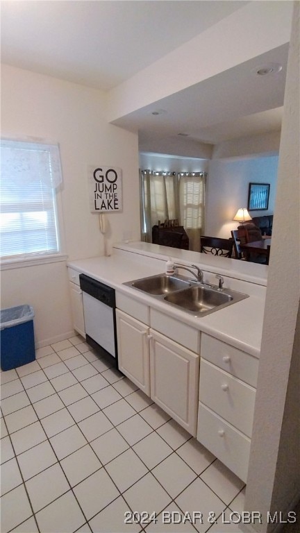 kitchen with white dishwasher, white cabinets, sink, light tile patterned floors, and kitchen peninsula