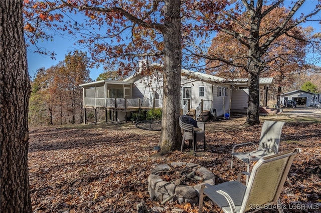 back of property featuring an outdoor fire pit and a sunroom