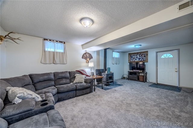 living room featuring carpet flooring, a wood stove, and a textured ceiling