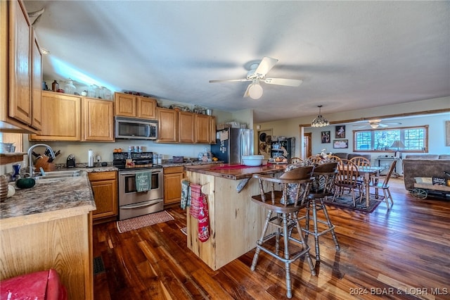 kitchen with a breakfast bar, sink, stainless steel appliances, and dark wood-type flooring