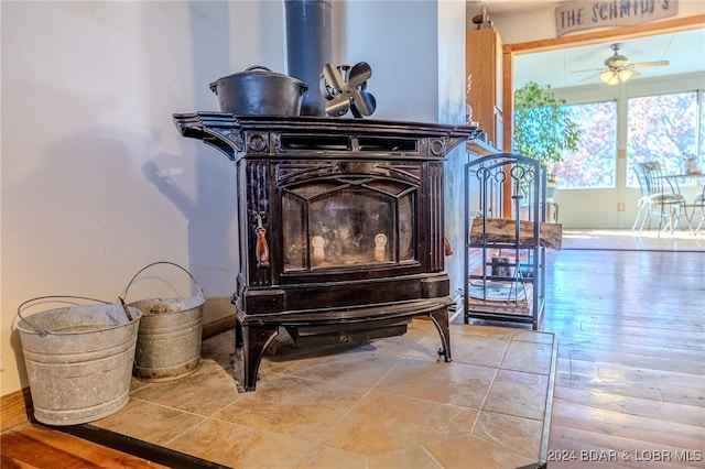 room details with ceiling fan, wood-type flooring, and a wood stove