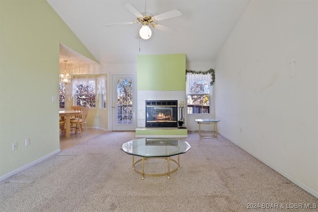 unfurnished living room featuring ceiling fan with notable chandelier, a fireplace, carpet floors, and lofted ceiling