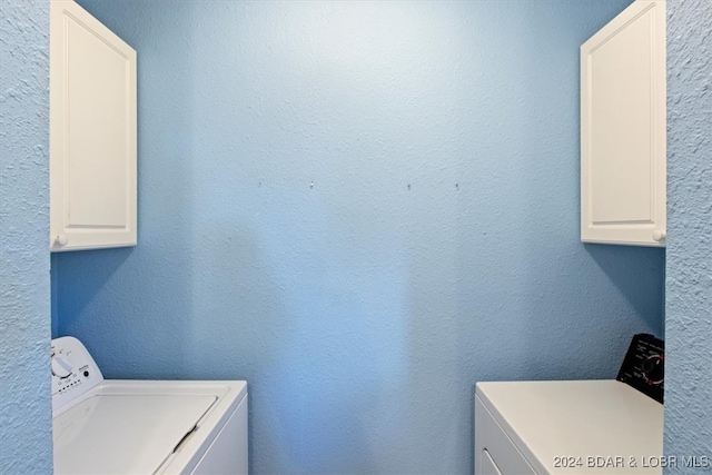 clothes washing area with cabinets and washing machine and clothes dryer