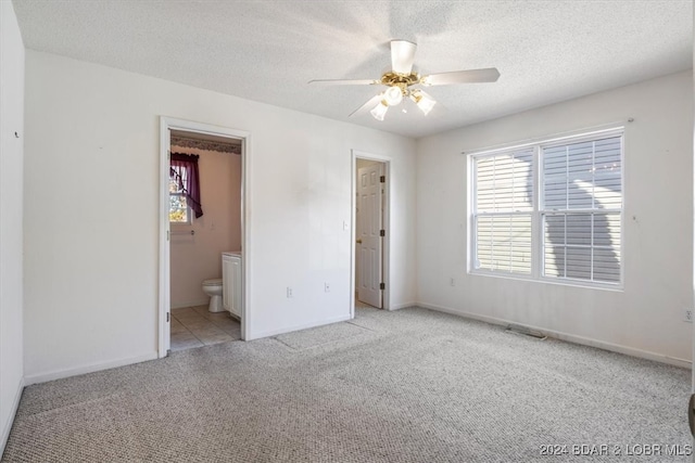 unfurnished bedroom featuring light carpet, a textured ceiling, and ensuite bathroom