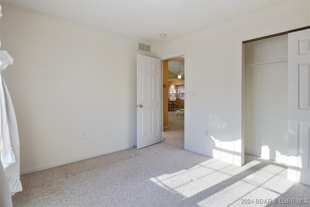 unfurnished bedroom featuring light carpet and a closet