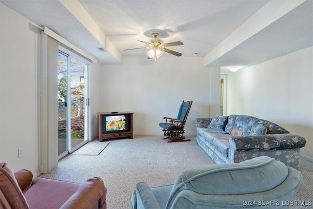 living room with ceiling fan, light colored carpet, and a textured ceiling