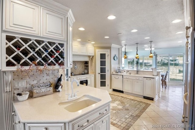 kitchen with backsplash, sink, white cabinets, and hanging light fixtures