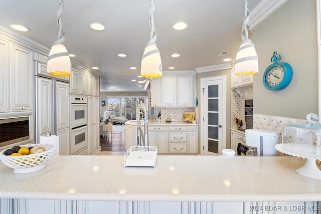 kitchen featuring white cabinets, white double oven, hanging light fixtures, and ornamental molding