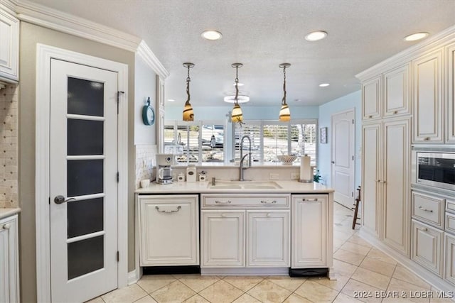 kitchen with ornamental molding, a textured ceiling, sink, pendant lighting, and light tile patterned floors