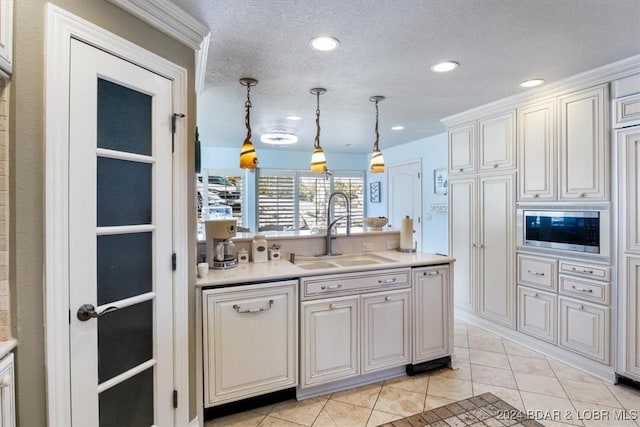 kitchen with light tile patterned flooring, a textured ceiling, decorative light fixtures, and sink