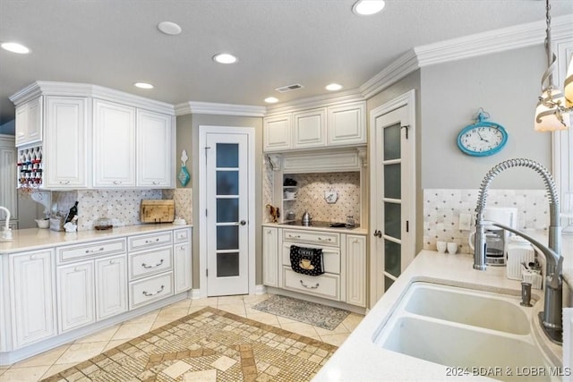 kitchen with backsplash, white cabinetry, sink, and hanging light fixtures