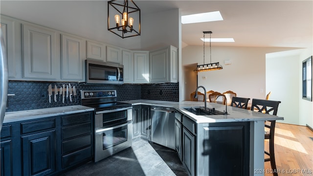 kitchen with a breakfast bar area, backsplash, lofted ceiling with skylight, and appliances with stainless steel finishes