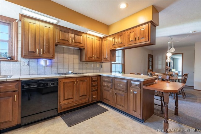 kitchen with tile counters, gas stovetop, tasteful backsplash, black dishwasher, and kitchen peninsula