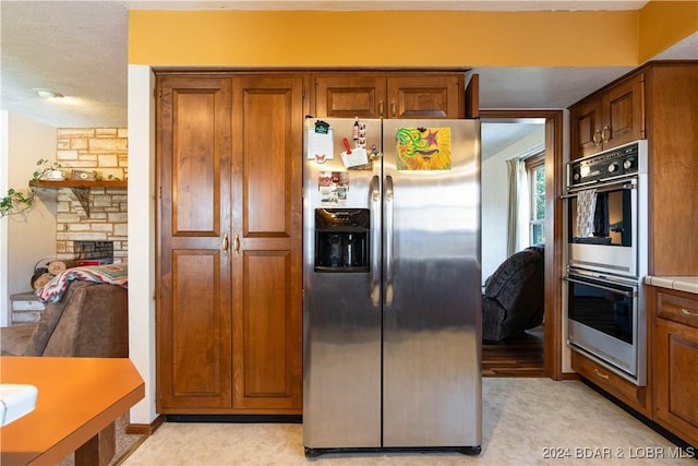 kitchen featuring light colored carpet, a textured ceiling, and appliances with stainless steel finishes