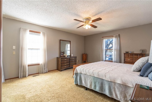 carpeted bedroom featuring ceiling fan and a textured ceiling