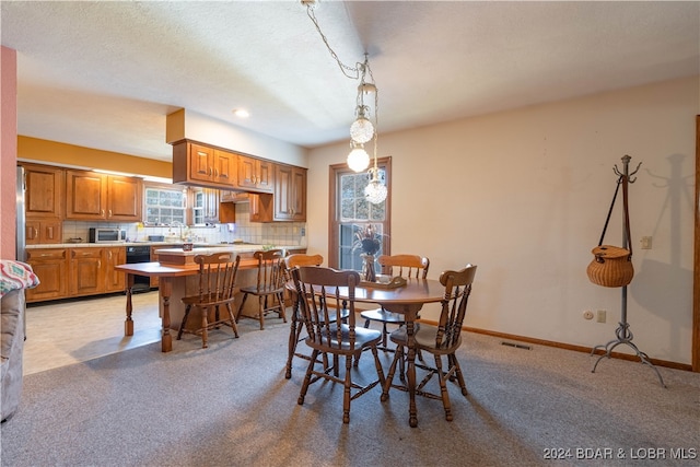 dining area featuring a textured ceiling and light colored carpet