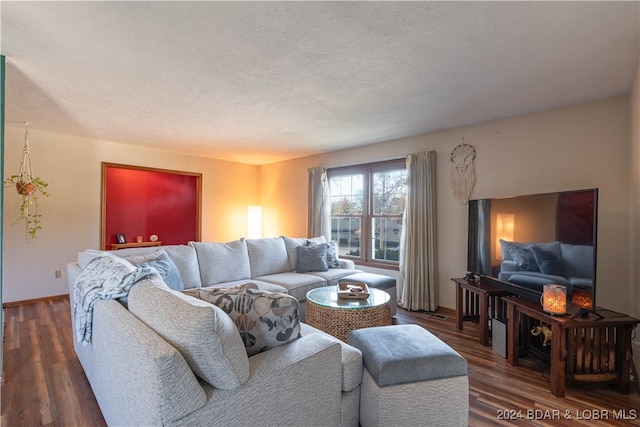 living room with a textured ceiling and dark wood-type flooring