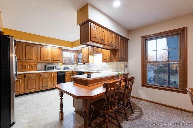 kitchen with plenty of natural light, decorative backsplash, sink, and stainless steel refrigerator