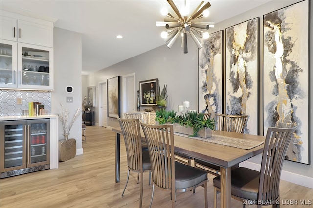 dining space with a chandelier, light wood-type flooring, indoor bar, and wine cooler