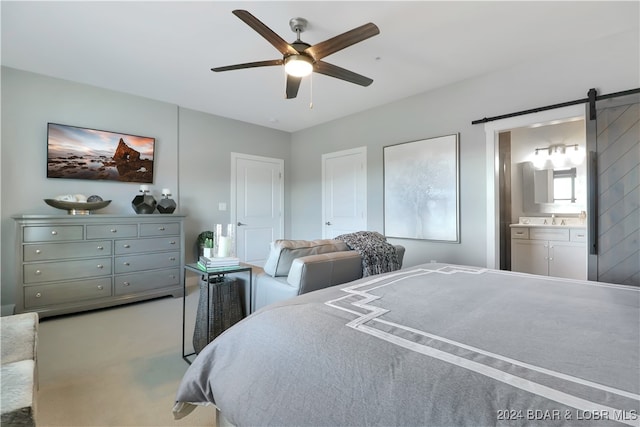 carpeted bedroom featuring ceiling fan, a barn door, sink, and ensuite bathroom