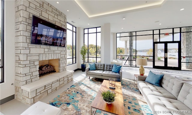 living room with a tray ceiling, floor to ceiling windows, a fireplace, and french doors