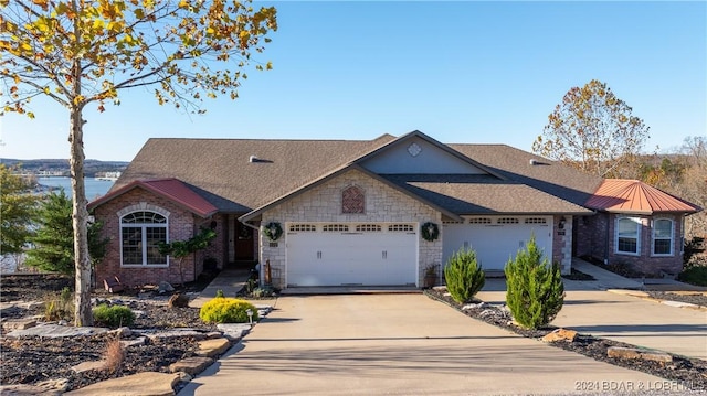 ranch-style home with a garage and a water view