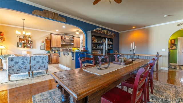 dining room featuring ornamental molding, ceiling fan with notable chandelier, and light tile patterned floors