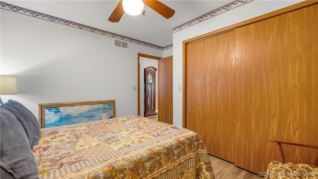 bedroom with ceiling fan, light hardwood / wood-style floors, and a closet