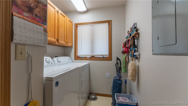 washroom with electric panel, washer and dryer, and cabinets