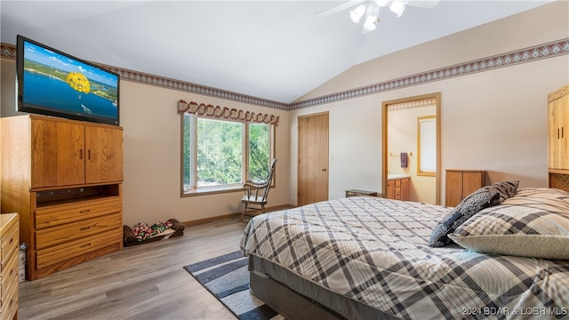 bedroom featuring light wood-type flooring, ensuite bathroom, ceiling fan, and lofted ceiling