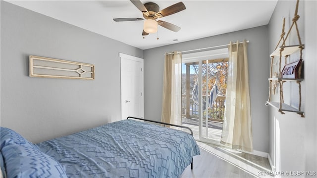 bedroom with hardwood / wood-style floors, access to outside, and ceiling fan