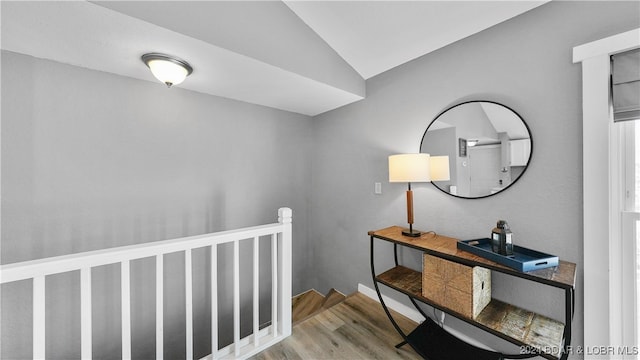 hallway with light hardwood / wood-style floors and lofted ceiling