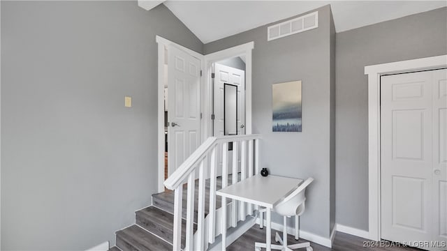 stairs with hardwood / wood-style flooring and vaulted ceiling