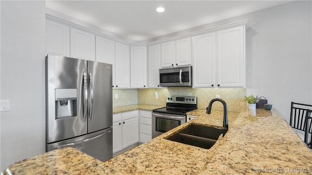 kitchen with sink, stainless steel appliances, tasteful backsplash, kitchen peninsula, and white cabinets